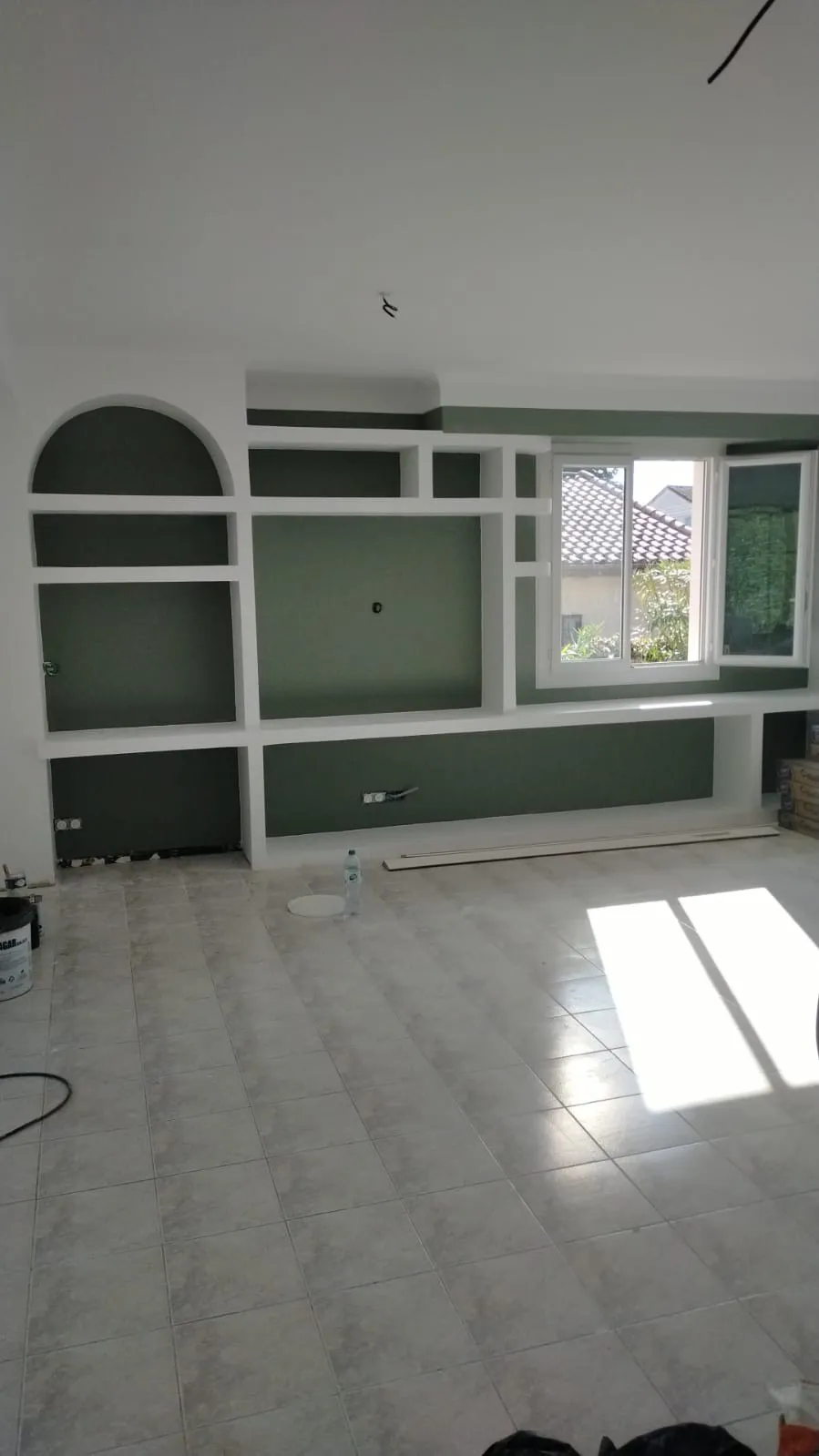 Bibliothèque murale sur mesure en plaques de plâtre peinte en vert olive, avec arche